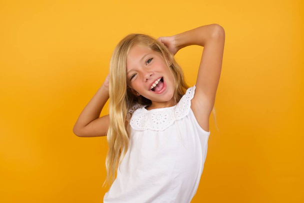 cute  girl  with hands behind head   on yellow background  - Photo, Image