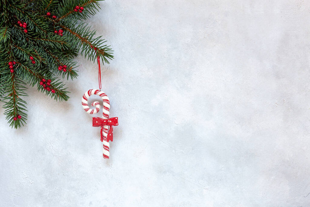 Christmas holiday background with fir-tree branches, red berries and Santa's stripes cane. Top view, close up on white background. - Photo, image
