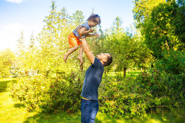 Portrait of cute baby boy with Down syndrome playing with dad in summer day on nature - Photo, Image