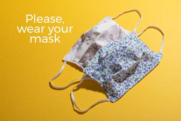 Παρακαλώ, φορέστε την αφίσα της μάσκας σας για προειδοποίηση στην είσοδο. Δύο φλοράλ μάσκες προσώπου και λευκές λέξεις. Όμορφη και πολύχρωμο σύμβολο συμβουλές για την υποχρεωτική χρήση της προστατευτικής υγιεινής μάσκα - Φωτογραφία, εικόνα