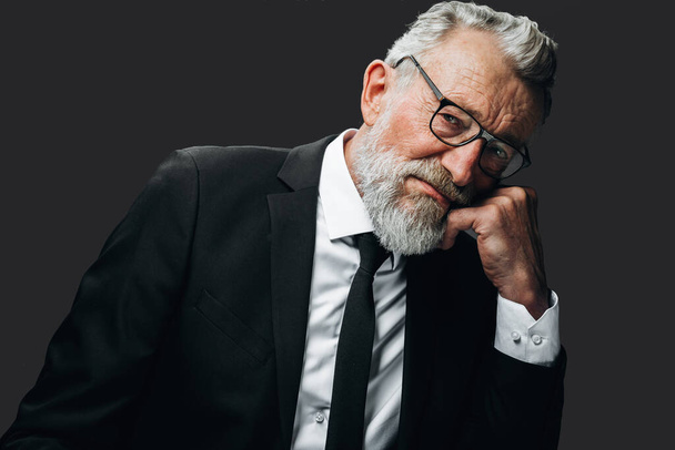 Mature bearded businessman in black formal suit thinking with his hand over chin - Φωτογραφία, εικόνα
