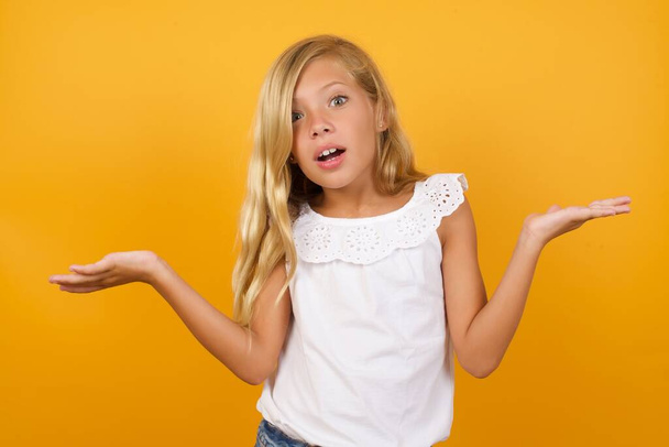 cute  girl is confused   on yellow background  - Foto, Bild