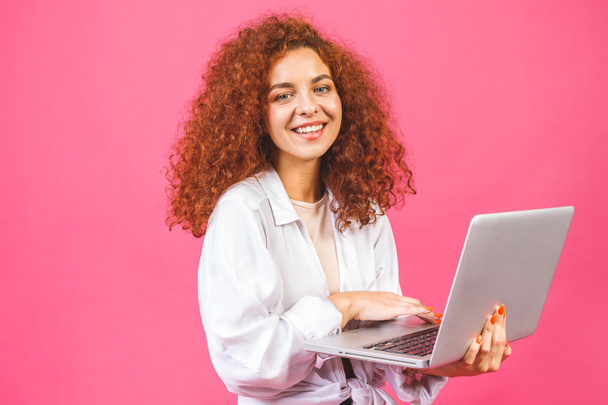Pretty young business woman in casual holding laptop, isolated over pink background.  - Фото, зображення