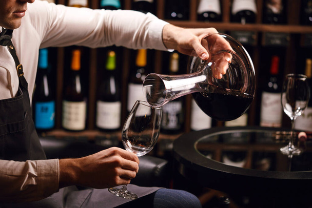 Expert decanting and pouring wine into glass. Staff training for sommelier - 写真・画像