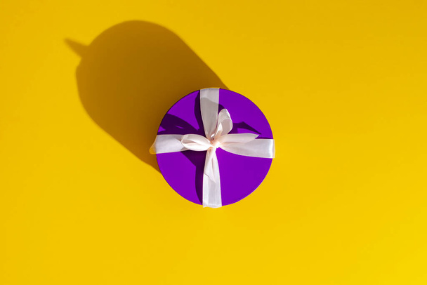 a violet gift box on yellow background. - Φωτογραφία, εικόνα