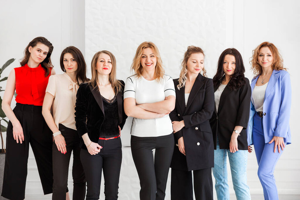 группа женщин, одетых в бизнес-стиль позирующих и смотрящих в камеру. Горизонтальное фото - Фото, изображение