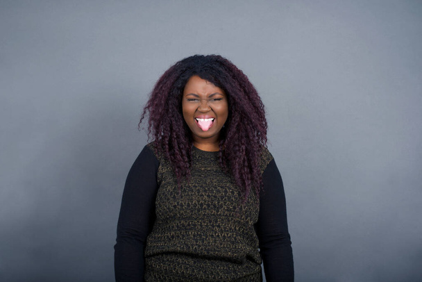 Körpersprache. Ekelhaft gestresste hübsche Afroamerikanerin in lässiger Kleidung posiert vor grauer Wand, runzelt die Stirn und demonstriert Abneigung gegen etwas. - Foto, Bild