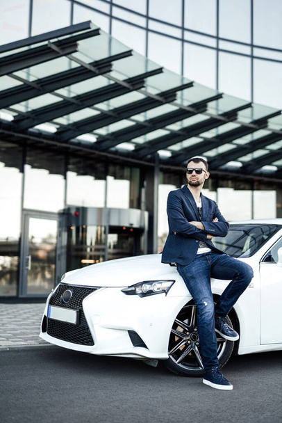 Serious empresario masculino está de pie con su auto en la ciudad - Foto, imagen
