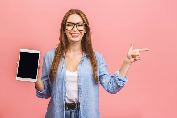 Lässig lächelnde Geschäftsfrau mit leerem Tablet-Computer-Bildschirm vor rosa Hintergrund. Blick in die Kamera. - Foto, Bild