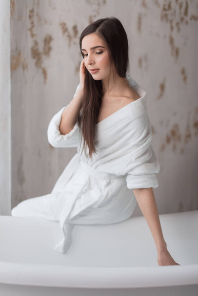 Beautiful young woman posing in bathrobe before taking bath - Foto, Imagen