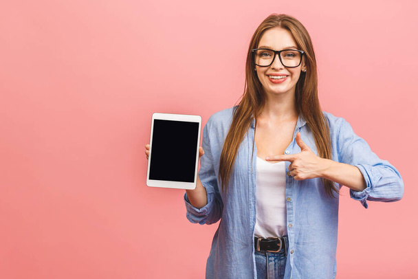 Casual smiling business woman showing blank tablet computer screen over pink background. Looking at camera. - Zdjęcie, obraz