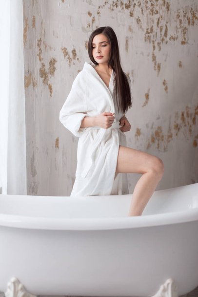 Beautiful young woman posing in bathrobe before taking bath - Foto, Imagem