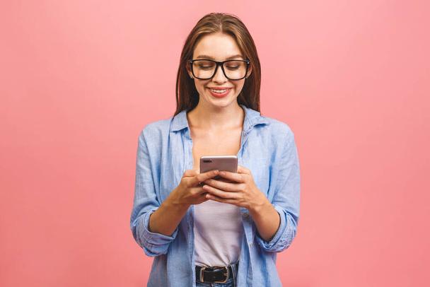 Портрет щасливої молодої ділової жінки з використанням мобільного телефону ізольовано на рожевому фоні
. - Фото, зображення