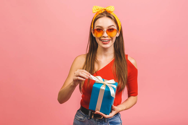 Sonriente joven hermosa mujer sostiene caja de regalo. Aislado sobre fondo rosa. Captura de estudio. - Foto, imagen