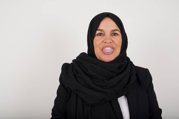美しい 若い イスラム 女性 黒 ヒジャブ ととも に 幸せ と 面白い 顔 笑顔 と 舌 示す. - 写真・画像