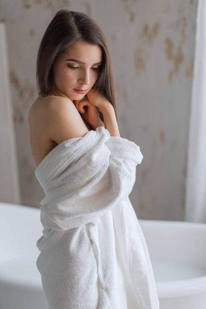 Spa Woman. Tender young woman with long brown hair in bath robe in bathroom. - Zdjęcie, obraz