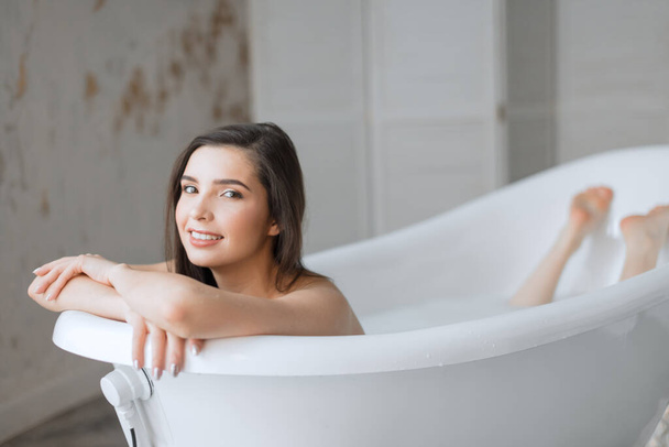 Woman relaxing in milk filled bath in spa centre - Zdjęcie, obraz
