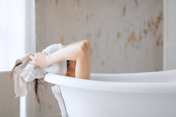 Attractive girl with open eyes takes a milk bath, touching towel on her head. - Foto, Bild