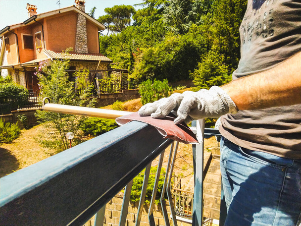 Eldivenli bir işçi çiti zımpara kağıdıyla temizler.. - Fotoğraf, Görsel