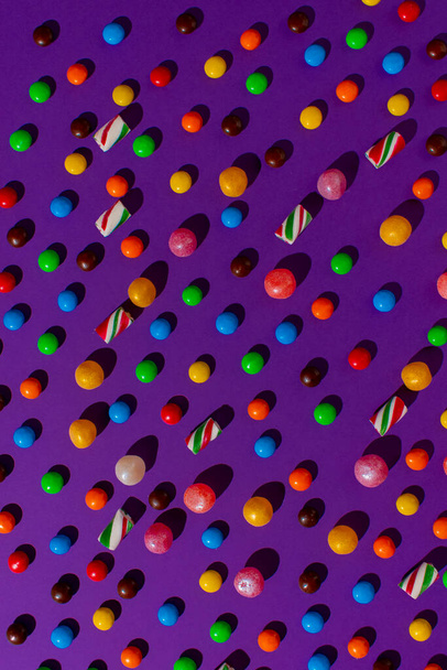 bright candy scattered on a flat purple background. View from above. Hard light. - Foto, immagini