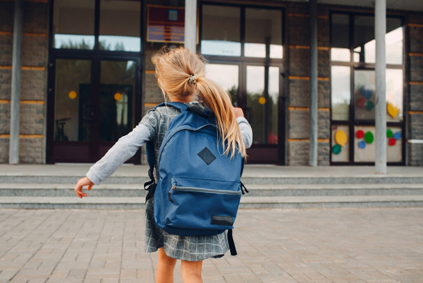 Aranyos kislány, hátizsákkal szalad vissza az iskolába. - Fotó, kép