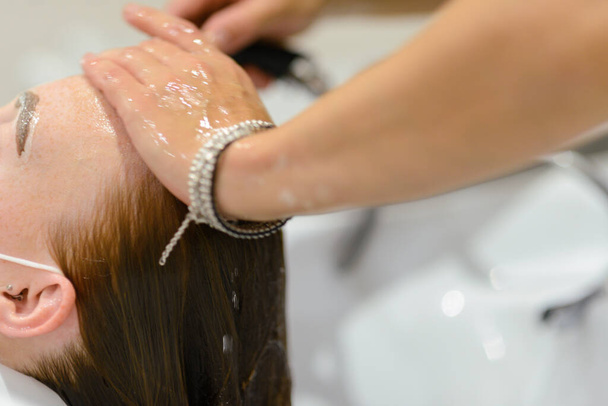 A closeup shot of a young female getting her hair washed in a hair salon - Zdjęcie, obraz