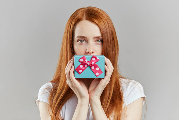 pretty red-haired girl with a gift posing to the camera - Fotó, kép