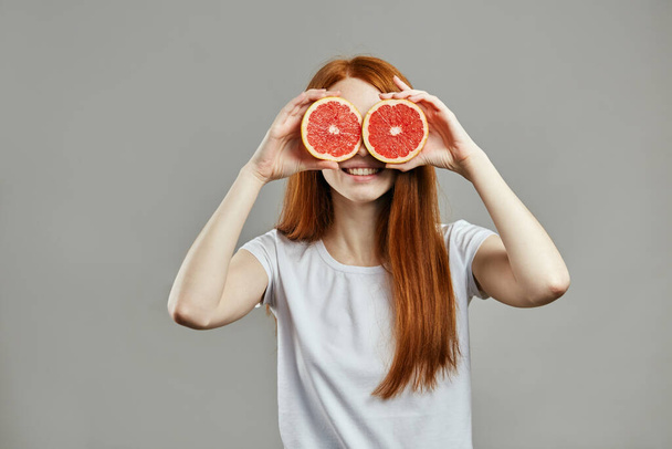 fubby red-haired girl with grapefruit on her eyes - Foto, imagen