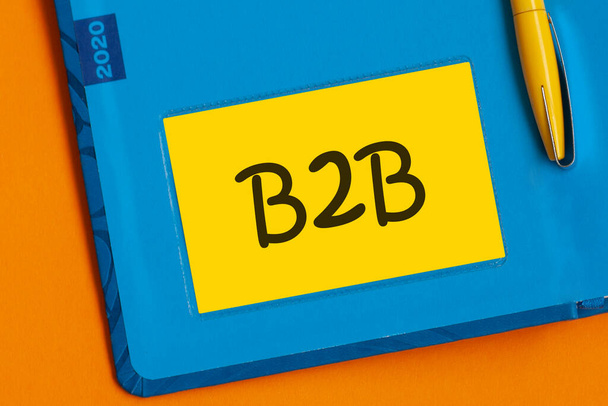 B2Bという言葉は、ノートのために黄色い紙に黒いマーカーで書かれています。B2Bビジネスからビジネスへ. - 写真・画像