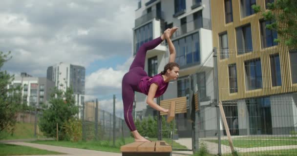 Mujer atlética hace torzal vertical de pie en el banco, ejercicios de estiramiento en el entorno urbano, clases de yoga al aire libre, entrenamiento físico y fitness en la ciudad, 4k 120p HQ de Prores - Metraje, vídeo