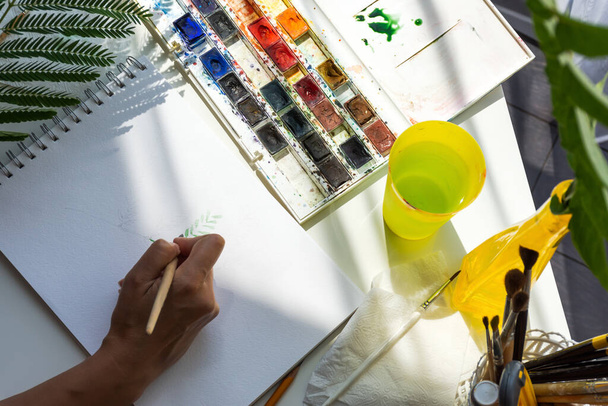De aquareltekening is het bovenaanzicht. Het meisje tekent met aquarellen. Creatief proces in de Studio. Kunstenaarsatelier. - Foto, afbeelding
