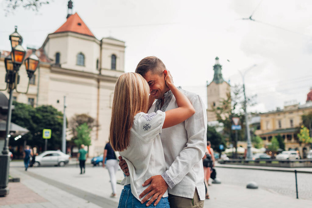 Jong stel verliefd wandelen in het oude Lviv stad dragen van traditionele Oekraïense shirts. man en vrouw knuffelen en kussen buiten - Foto, afbeelding