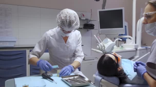 Dentista y asistente de preparación para la cirugía, batas blancas y máscaras, computadora del hospital - Imágenes, Vídeo