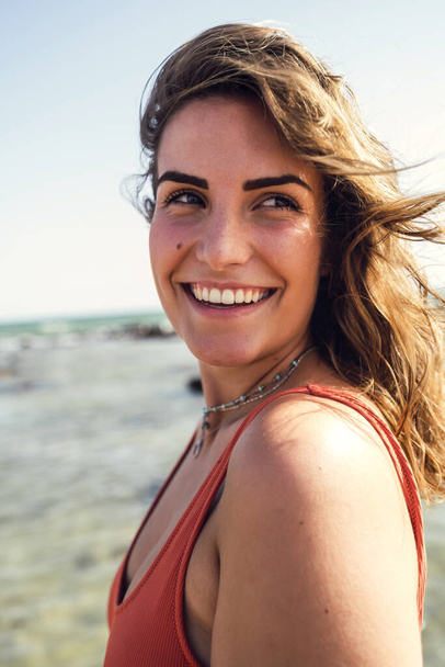 A closeup shot of a beautiful female in a swimsuit, smiling on Rota beach, Spain - Photo, Image