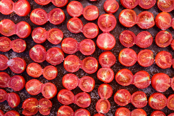 Los tomates frescos cortados en rodajas se espolvorean con sal y se echan en una tabla para secar y se fotografían desde arriba en italia - Foto, Imagen