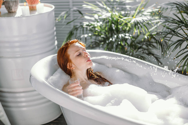 Portrait of happy young woman playing with foam in bathtub - Zdjęcie, obraz