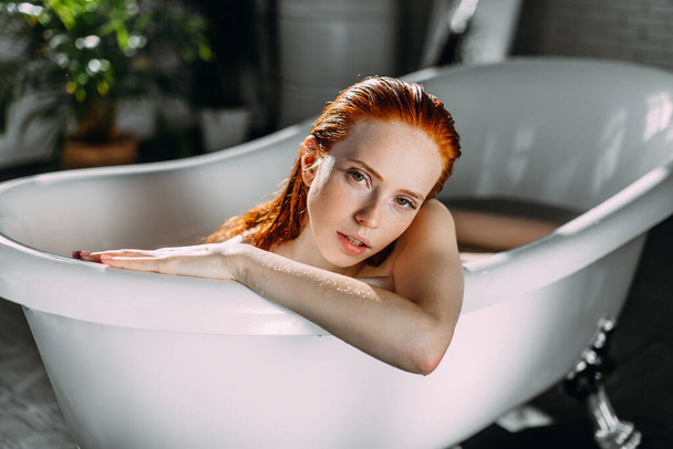Sensual woman with long ginger hair relaxing in water with tiny flowers - Foto, Imagem