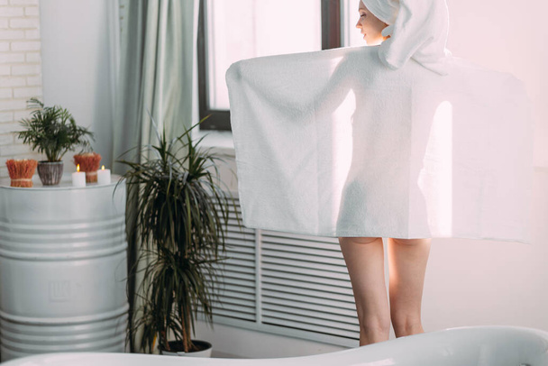Red-haired slim woman covering her body with towel while standing in bathroom - Foto, Imagem
