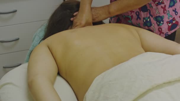 A masseuse giving a neck massage to woman lying down in spa - Footage, Video