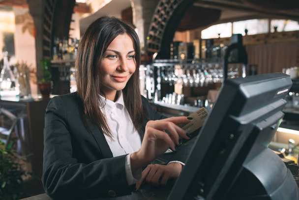small business, people and service concept - happy woman or waiter or manager in apron at counter with cashbox working at bar - Zdjęcie, obraz
