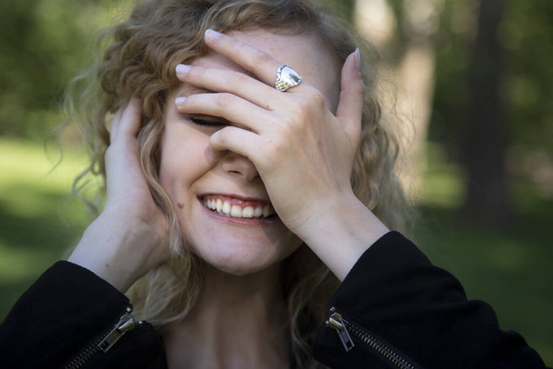 A closeup shot of a beautiful blonde female smiling and covering the half of her face with her hand - Foto, immagini