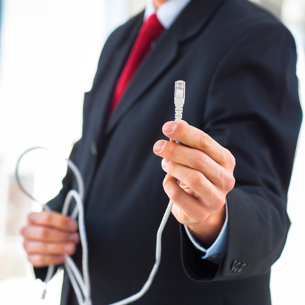 Businessman holding an ethernet cable - Photo, Image