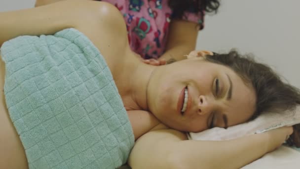 Raskaana oleva nainen hymyilee, kun hän saa käsivarren ja kaulan hieronta - Materiaali, video