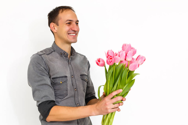 Mann mit Blumen. Romantiker Mann mit einem Strauß Tulpen zum Geburtstag. Glücklicher Frauentag. Blumenstrauß überreichen. Schöner Mann überreicht Blumen. Weißer Hintergrund. Horizontale Foto.s - Foto, Bild