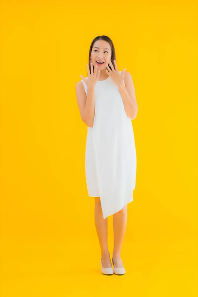 Портрет красивой молодой азиатской женщины в действии на желтом изолированном фоне - Фото, изображение