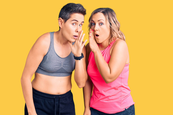 Un paio di donne che indossano abbigliamento sportivo mano sulla bocca raccontando voci segrete, sussurrando conversazione maliziosa  - Foto, immagini