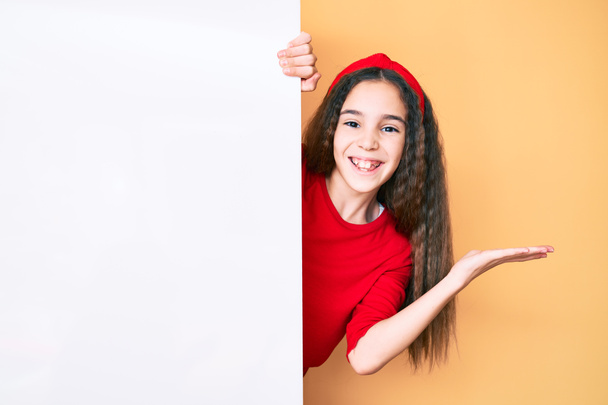 Aranyos spanyol gyerek lány kezében üres banner ünnepli győzelem boldog mosollyal és a győztes kifejezés emelt kézzel  - Fotó, kép
