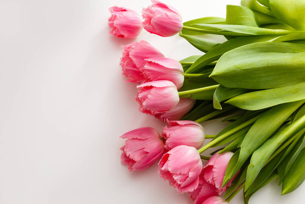 roze tulpen liggen op een witte tafel - Foto, afbeelding