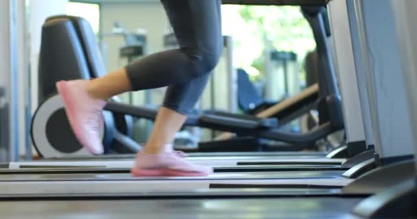 Κοντινό πλάνο των ποδιών των γυναικών που εργάζονται στο γυμναστήριο κάνοντας προπόνηση καρδιο τρέχει στο διάδρομο φορώντας ροζ πάνινα παπούτσια - Πλάνα, βίντεο