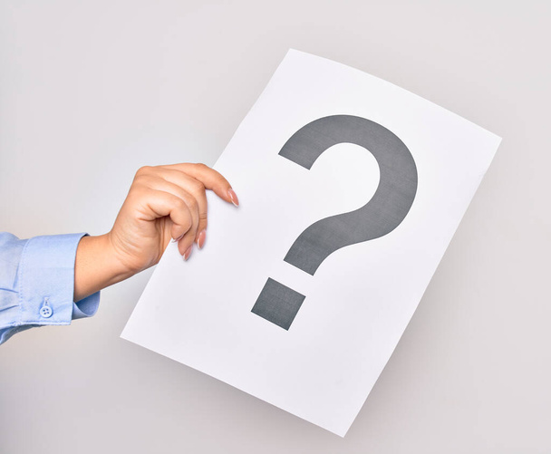 Hand of caucasian young woman holding paper with question mark symbol over isolated white background - Photo, Image